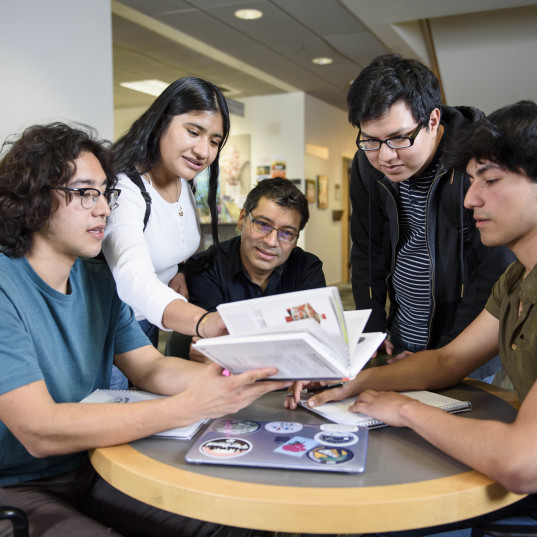 Students sitting around a table in Watzek looking at a book.