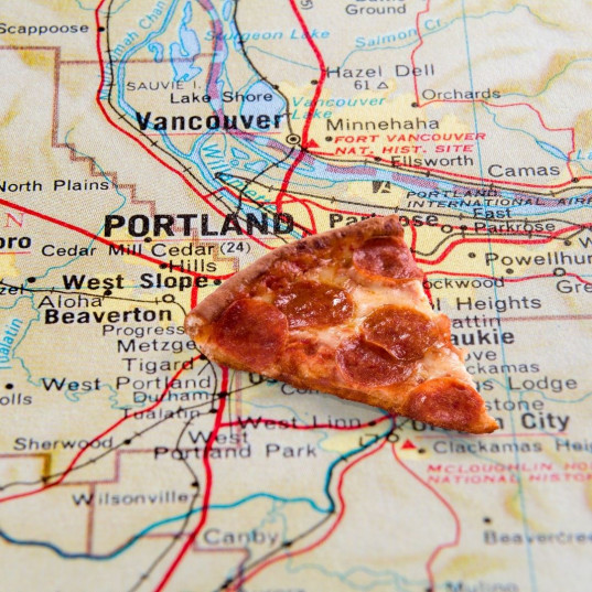 Slice of pepperoni pizza over a map of Portland.