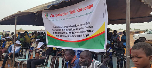 Opening ceremony of the screening campaign with attendees seated under a tent.