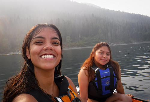 Image shows to women sitting on stand-up paddleboards and smiling at the camera