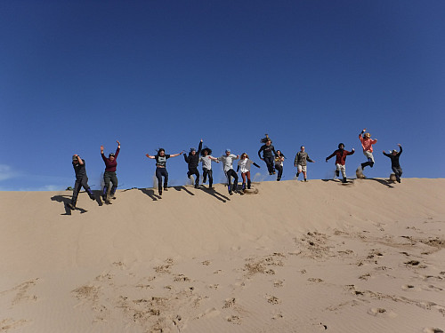 Students jumping and frolicking on coastal sand dunes