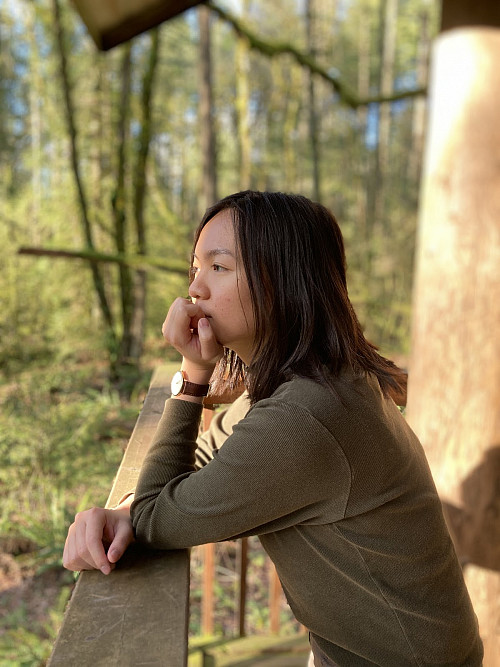 A student looks pensively into the forest