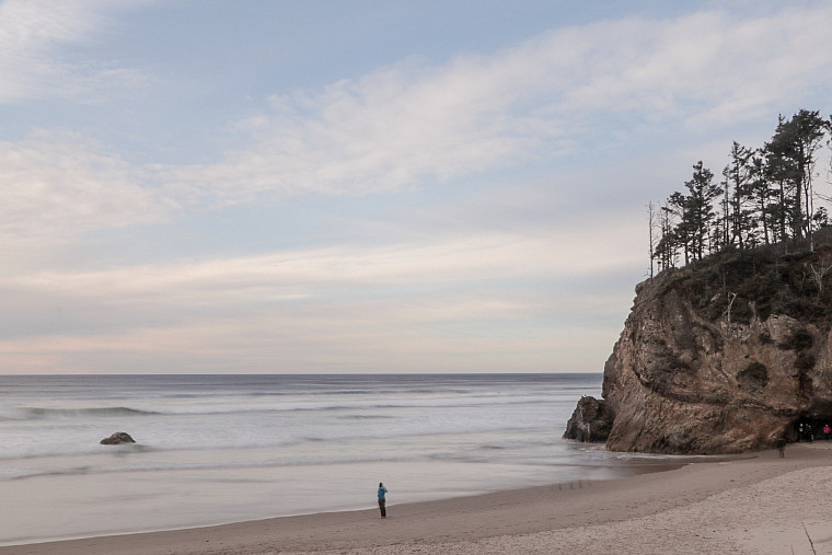 Picture shows an ocean beach with a person walking near the water