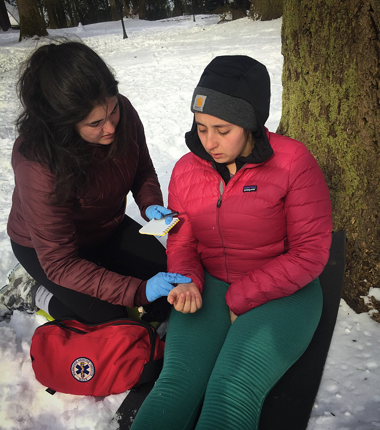 Wilderness First Responder measures the pulse of a patient