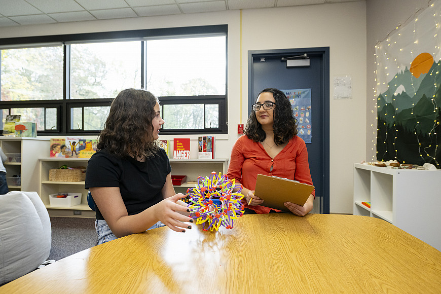 A school psychology graduate student works with a middle schooler at a table.