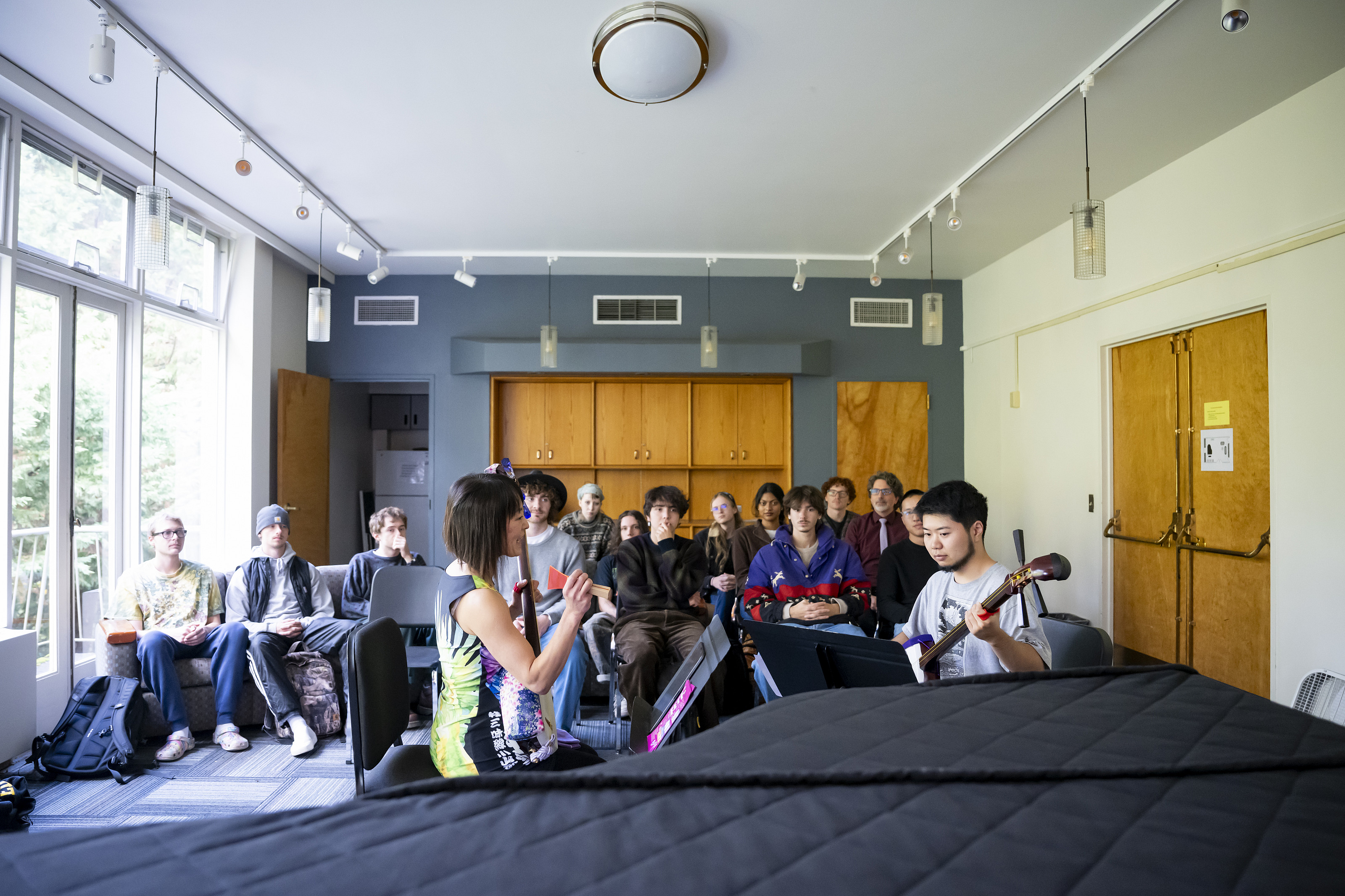 Two performers in front of a group of students in a classroom.