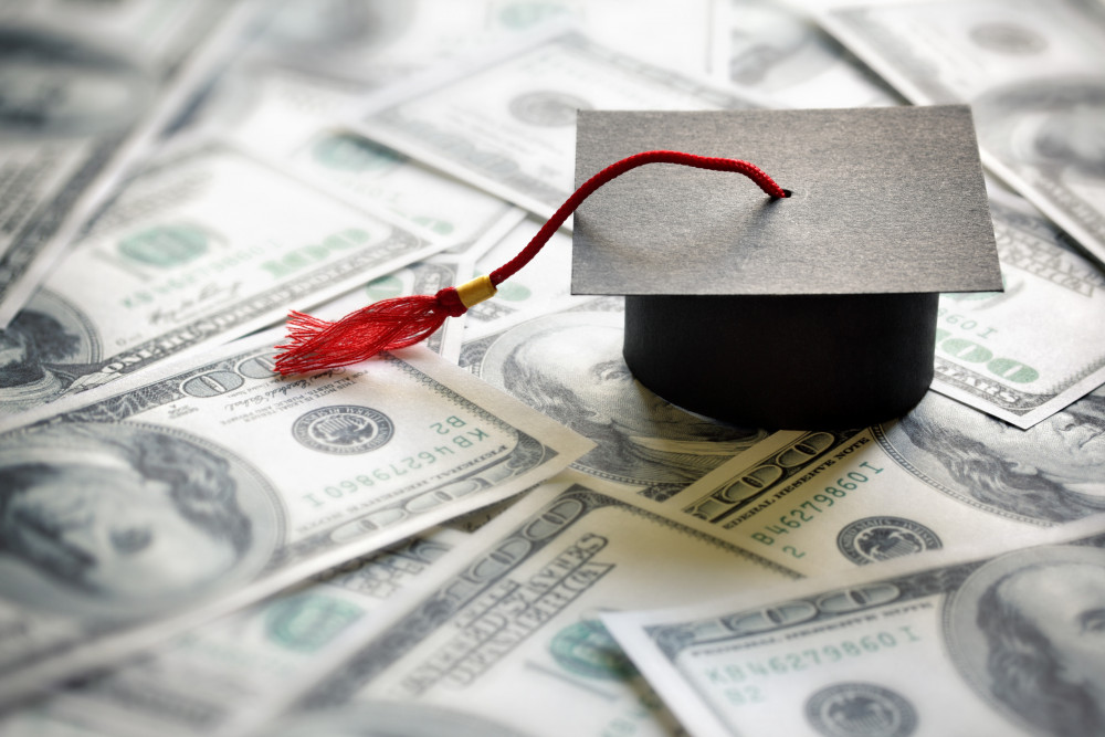 Graduation mortar board cap on one hundred dollar bills