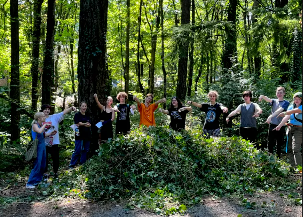 Students posing in front of a large pile of ivy that they pulled.