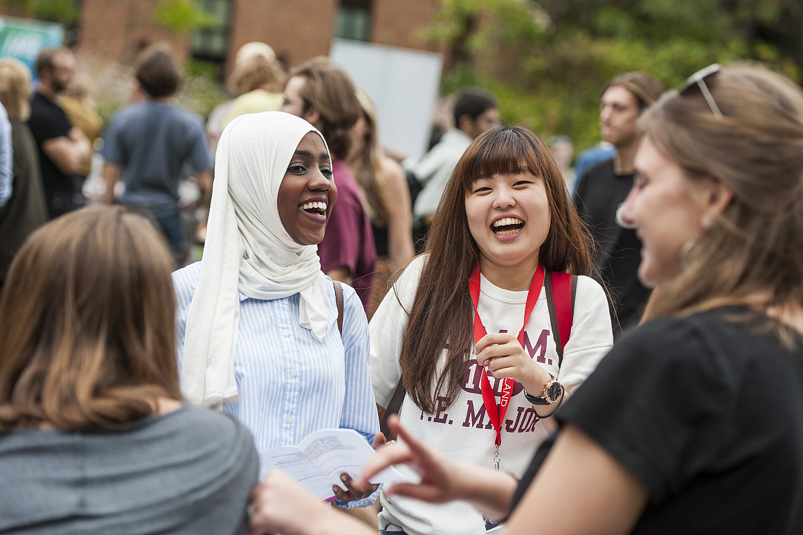 Two students laughing together at a student activity fair.