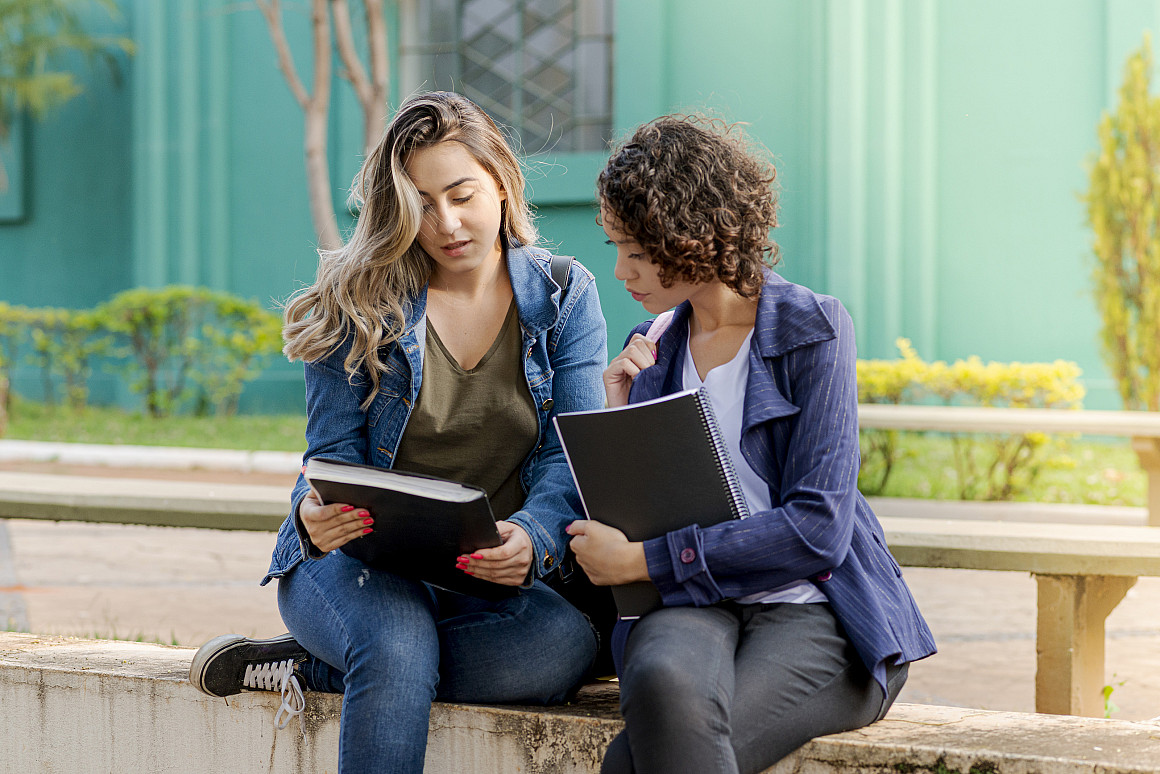 Two people sit together and look at a notebook.