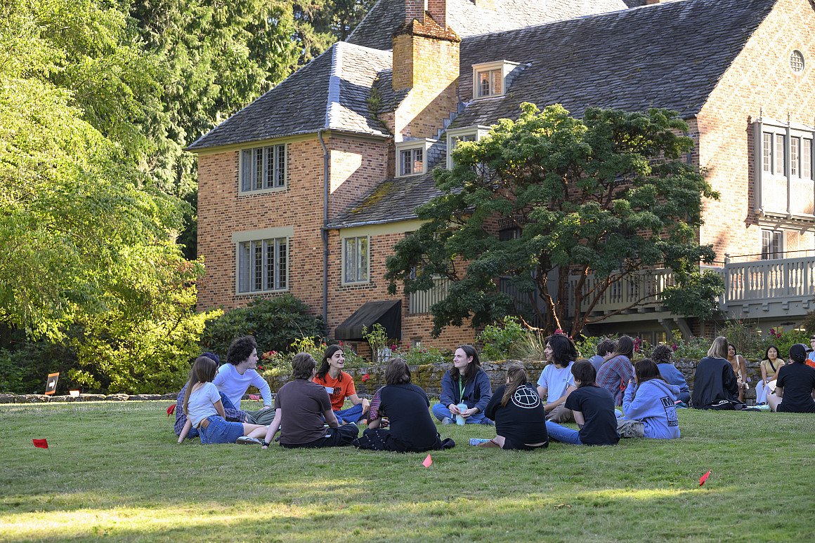 A group of students sitting together on the lawn by Frank Manor House.