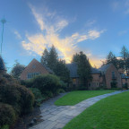 Exterior of Manor House with sun-dappled cloud behind it.