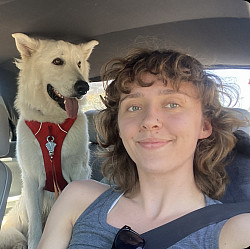 Kate smiling at the camera next to a dog.