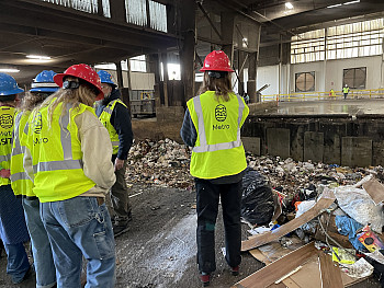 Students stand in front of a large pile of trash.