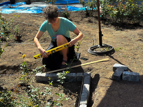 Student recobbling the edge of a garden bed