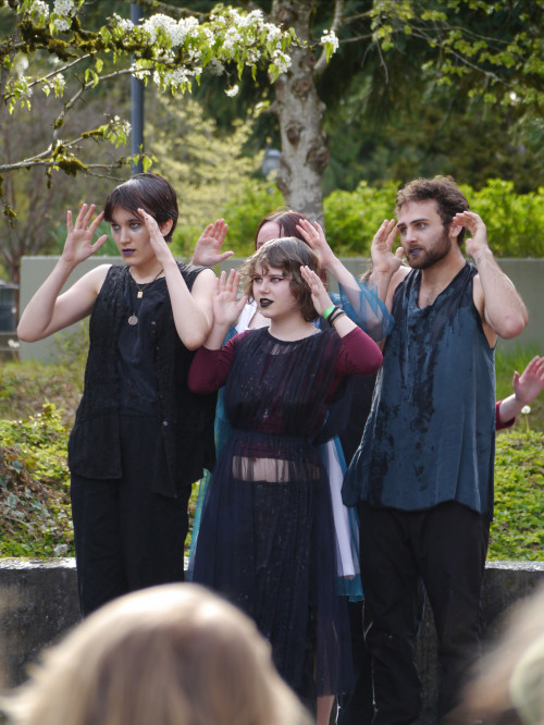 A group of students holding their hands up by their faces.