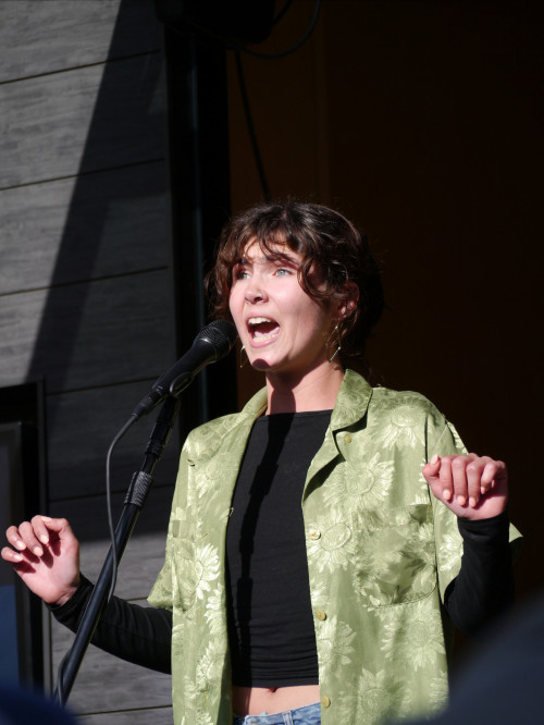 Lauren singing on stage, wearing a green top over a black shirt.