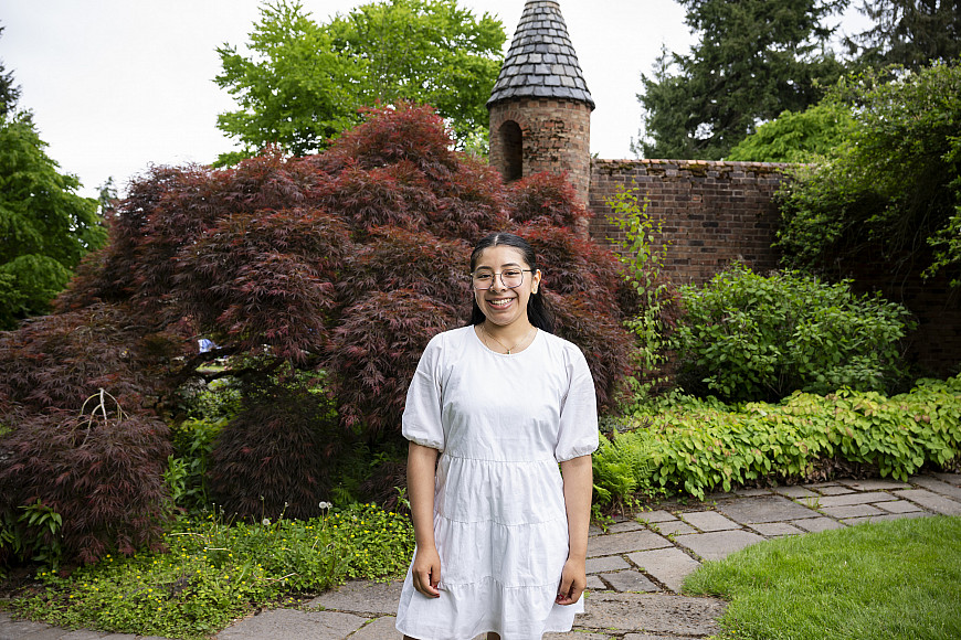 Azucena posing outside, wearing a white dress and glasses.
