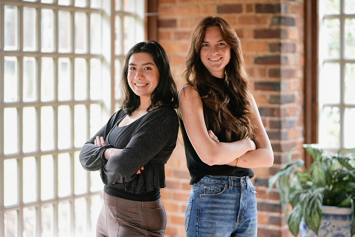 Kaia and Morgaine standing next to each other with their arms crossed, smiling at the camera.