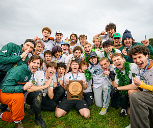 A group of student-athletes cheering and holding a trophy.